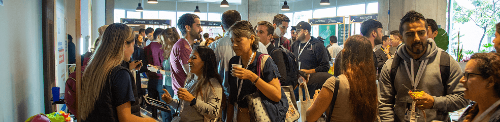 Zona de stands con asistentes interactuando y materiales promocionales de sponsors.