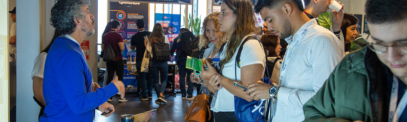 En la fotografía se percibe la interacción entre una encargada de stand con un asistente.