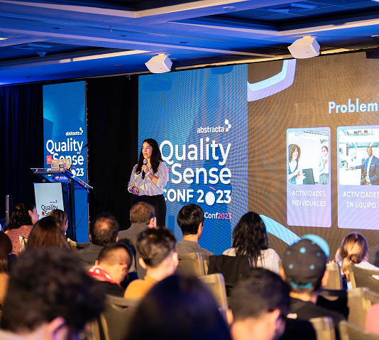 QSConf en Chile: speaker en el escenario con branding del evento.