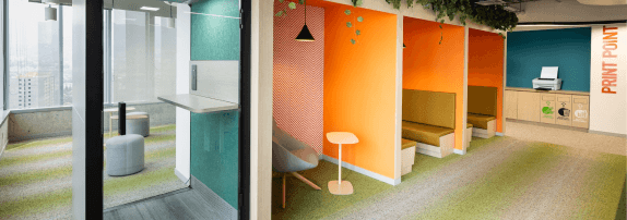 Fotografía que muestra zonas de oficinas coloridas con espacio dedicados a reuniones.